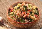 Bowl of quinoa salad with cucumber, tomato, and herbs