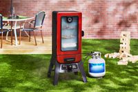 The Pit Boss propane smoker sits in a backyard, with a large Jenga set in the background..