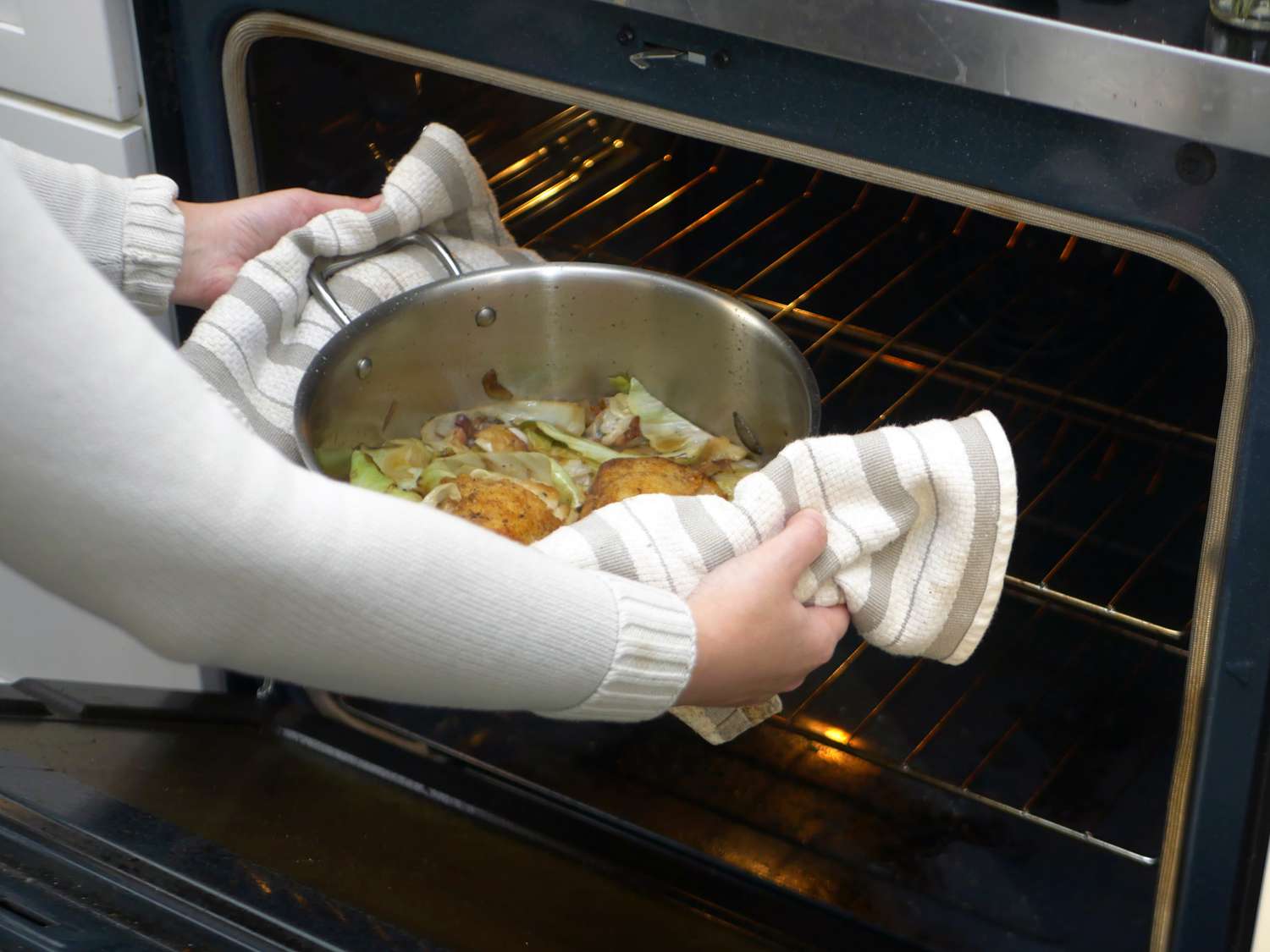 Taking a rondeau with braised chicken and cabbage out of the oven