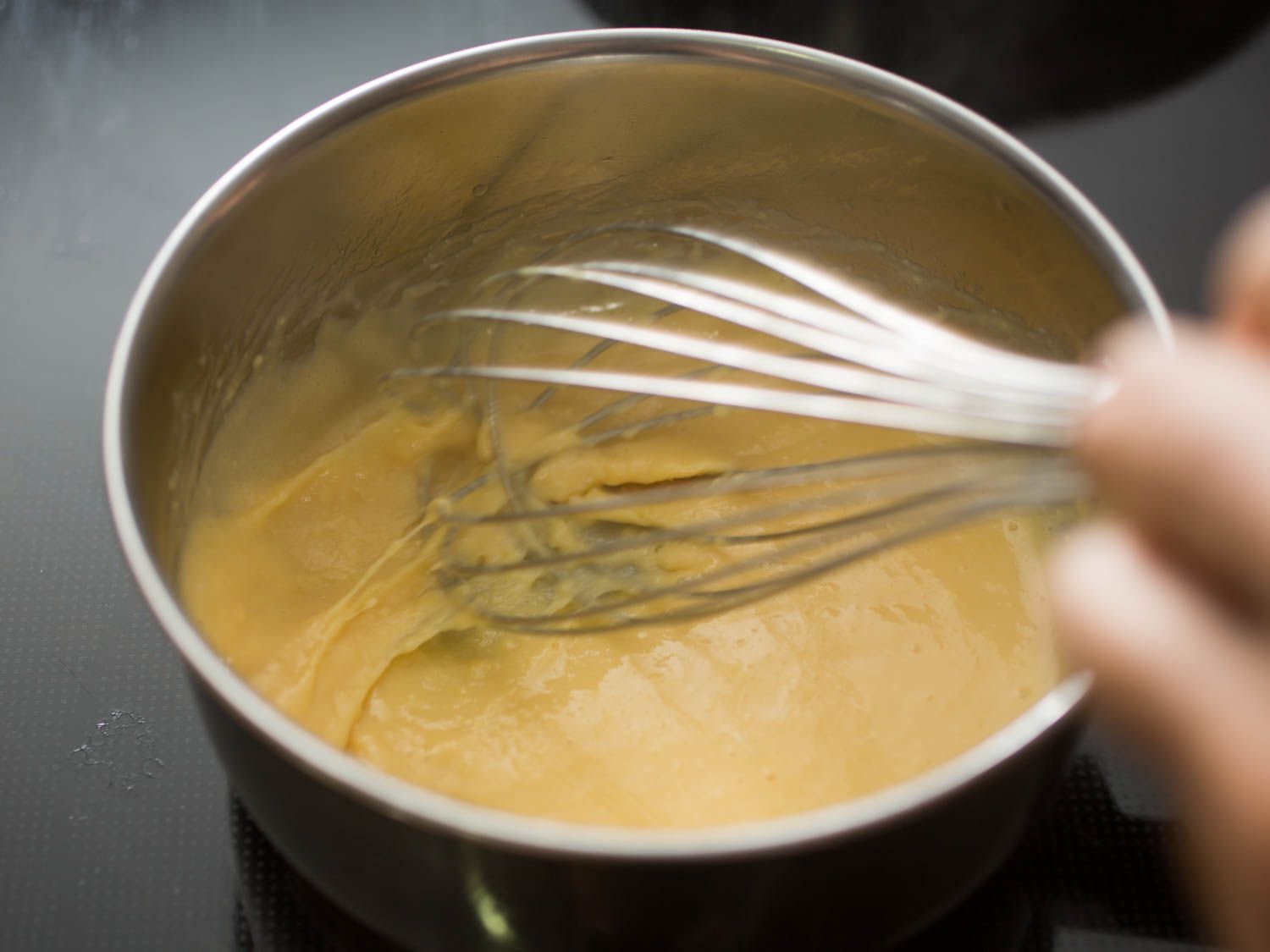 A whisk whisking constantly to keep fluffy curds from forming, leaving eggs silky smooth.