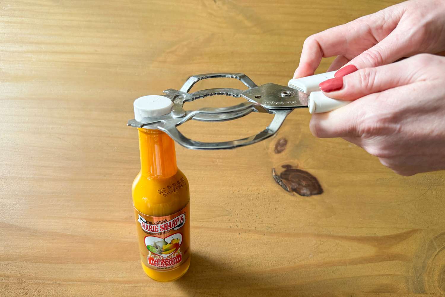 A metal jar opener around a jar of hot sauce