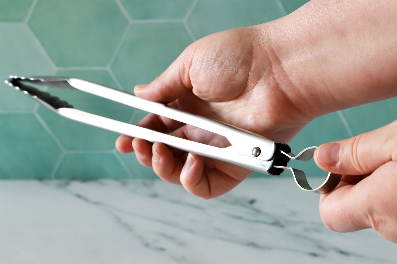 Hand holding the Cuisipro 12-Inch Stainless Steel Locking Tongs