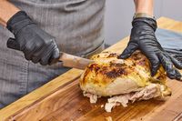 A person slices a chicken with the Miyabi Koh 9.5 Inch Slicing Knife