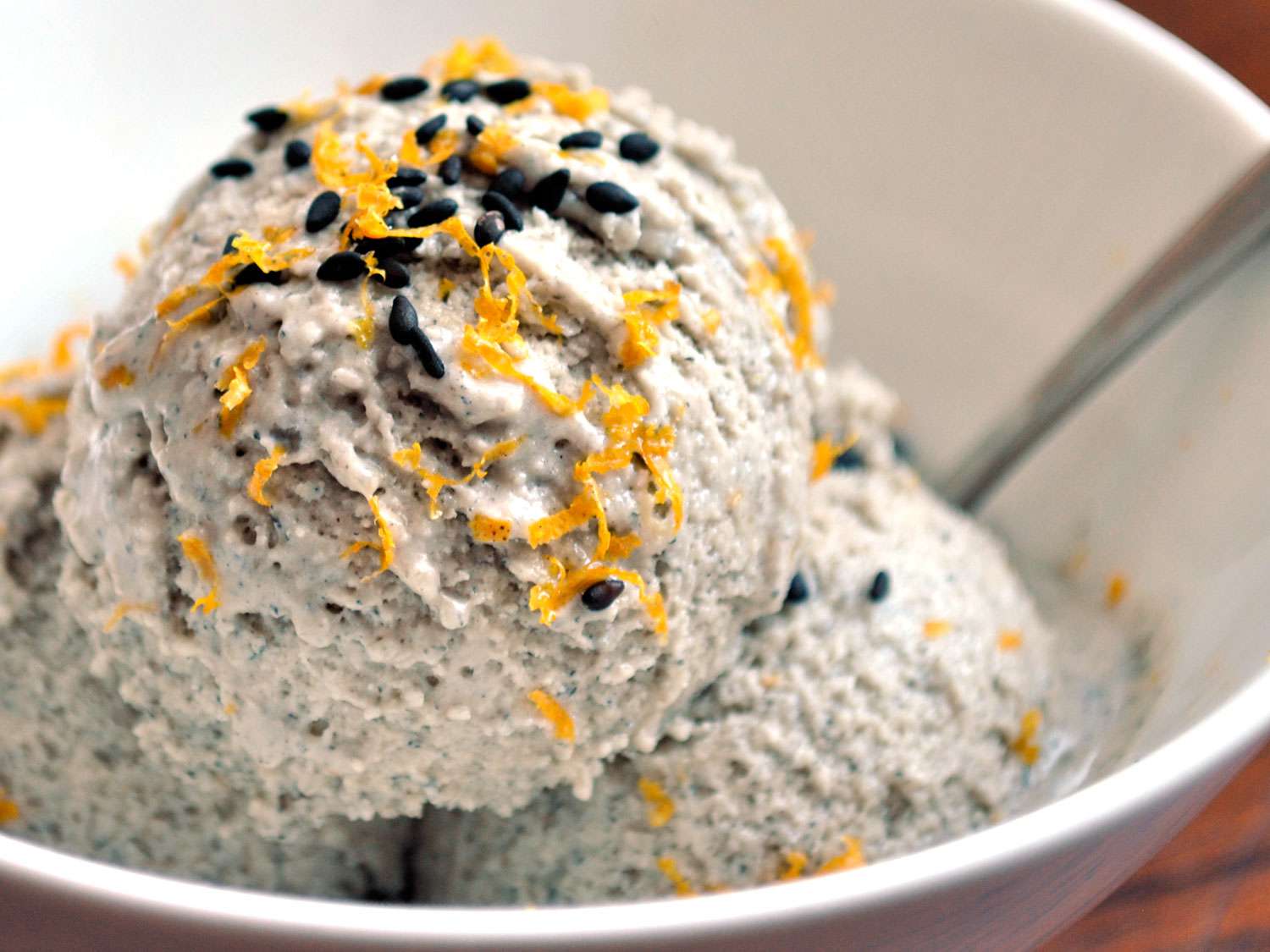 Three scoops of black sesame and orange ice cream in a bowl