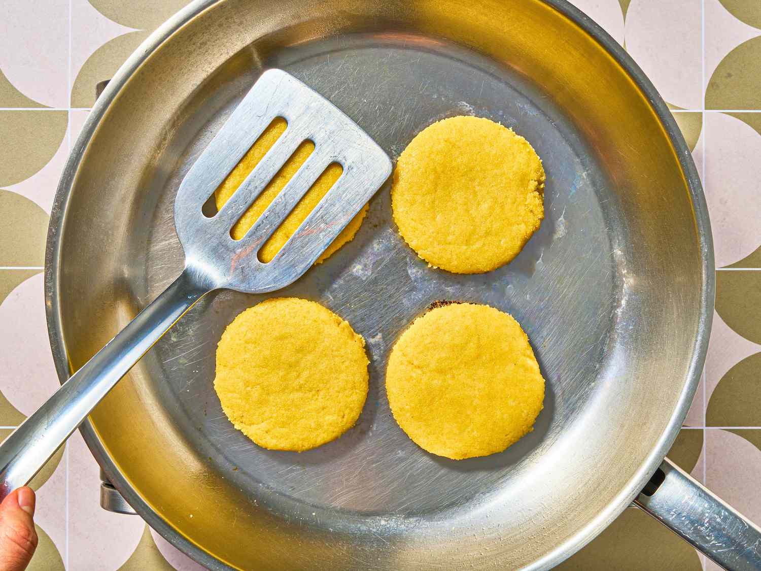 Overhead view of flattening harcha in pan