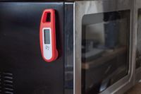 A magnetic instant-read thermometer attached to the of a microwave.