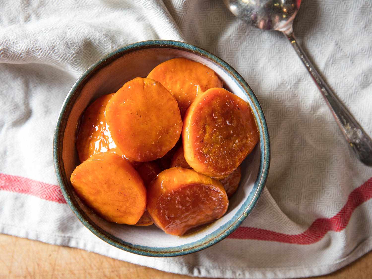 Candied yams (sweet potatoes) in a blue and white bowl with a white towel underneath.
