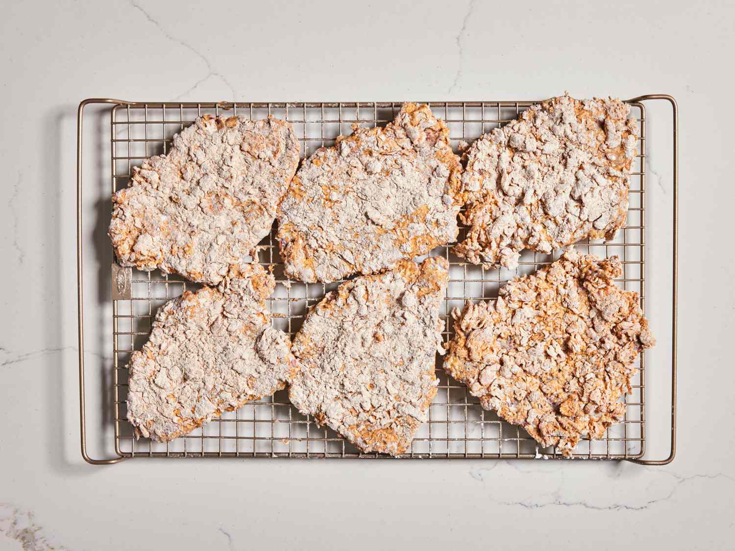 Six breaded steaks resting on a wire rack 