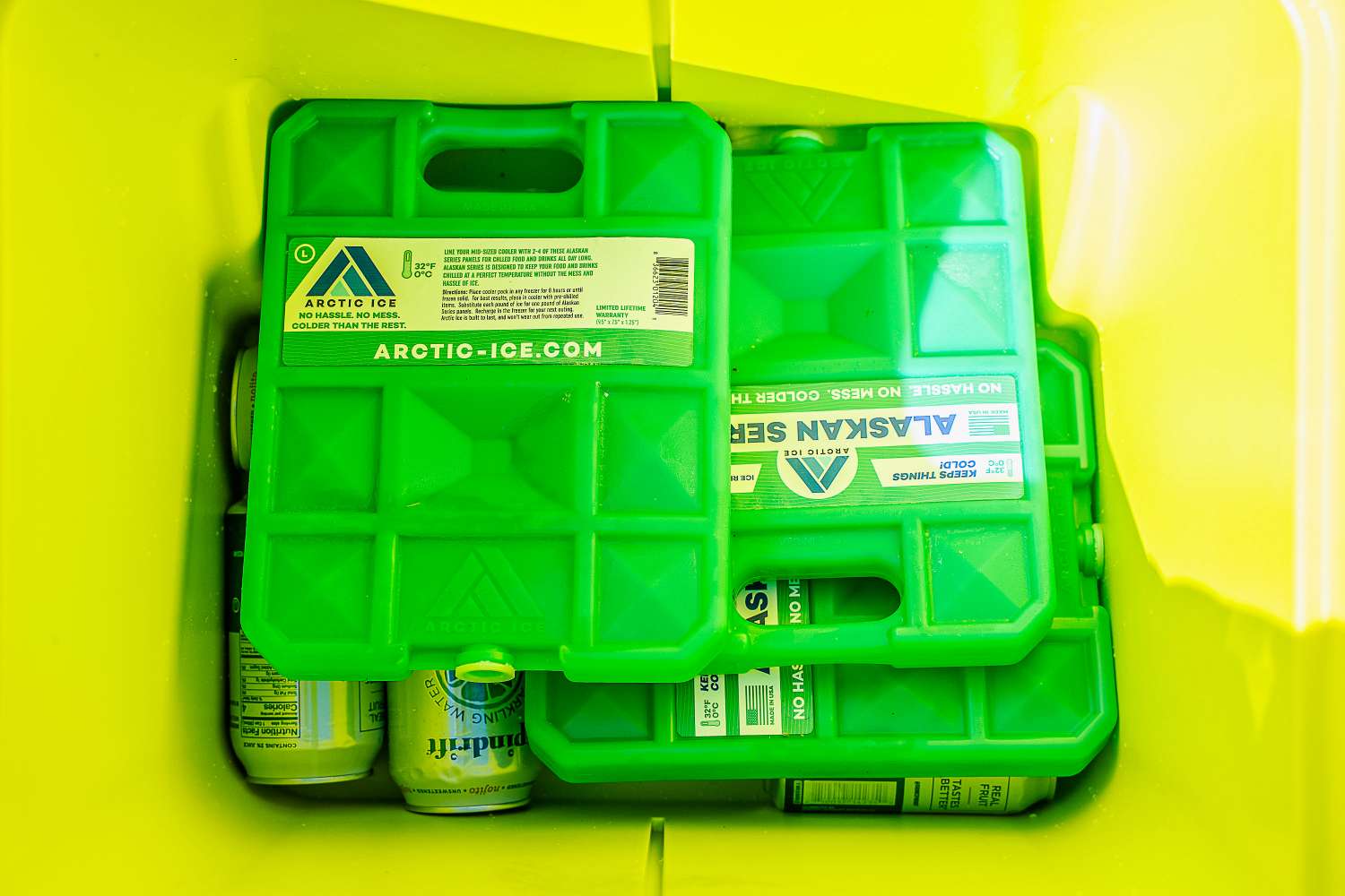 Green Arctic Ice packs inside a container, surrounded by beverage cans