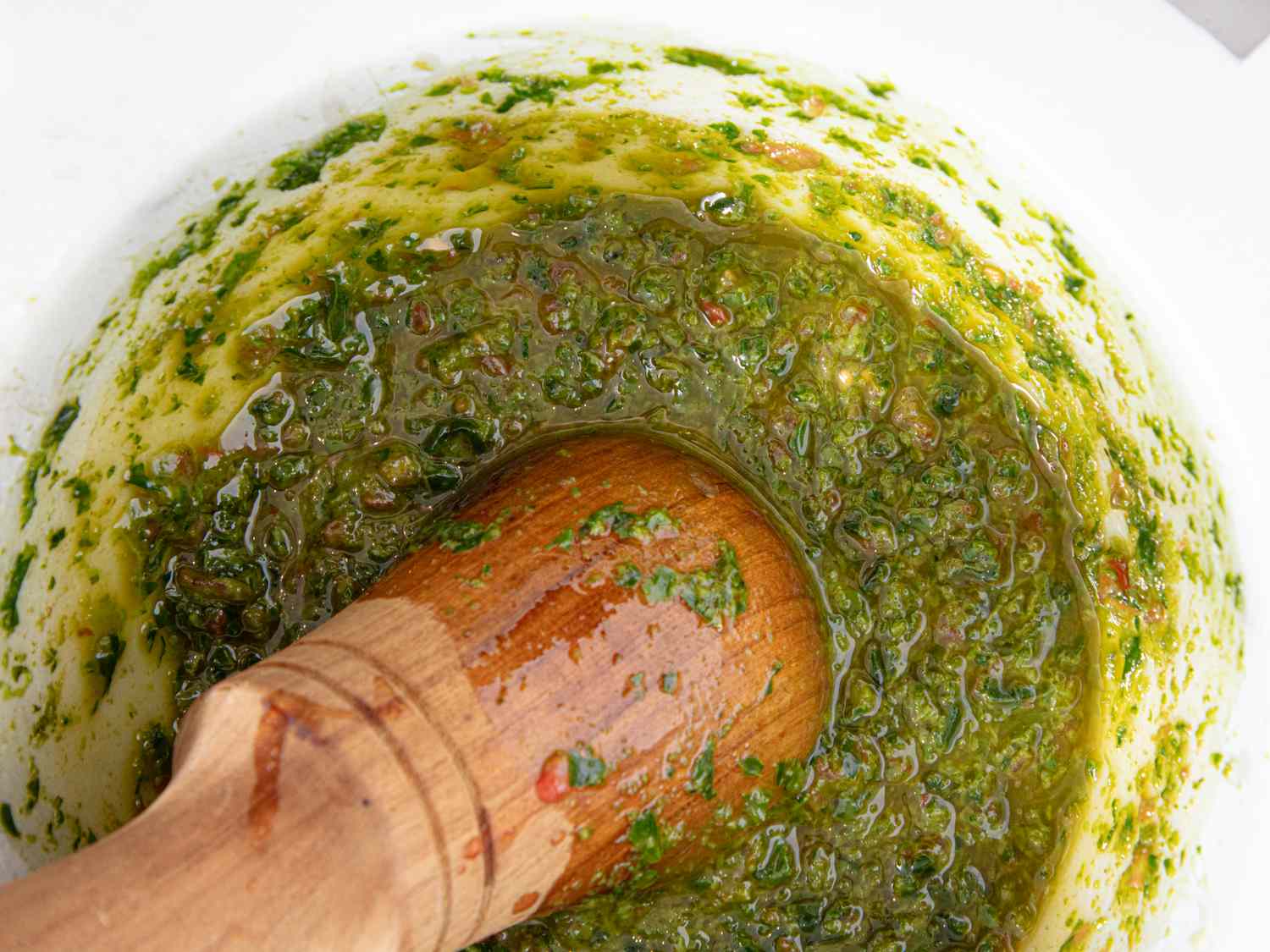A mortar and pestle filled with a green herb-based sauce (pistou)