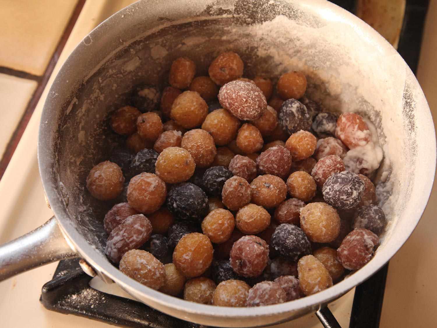 A stainless steel saucepan crusted with salt, holding salt-crusted roasted potatoes.