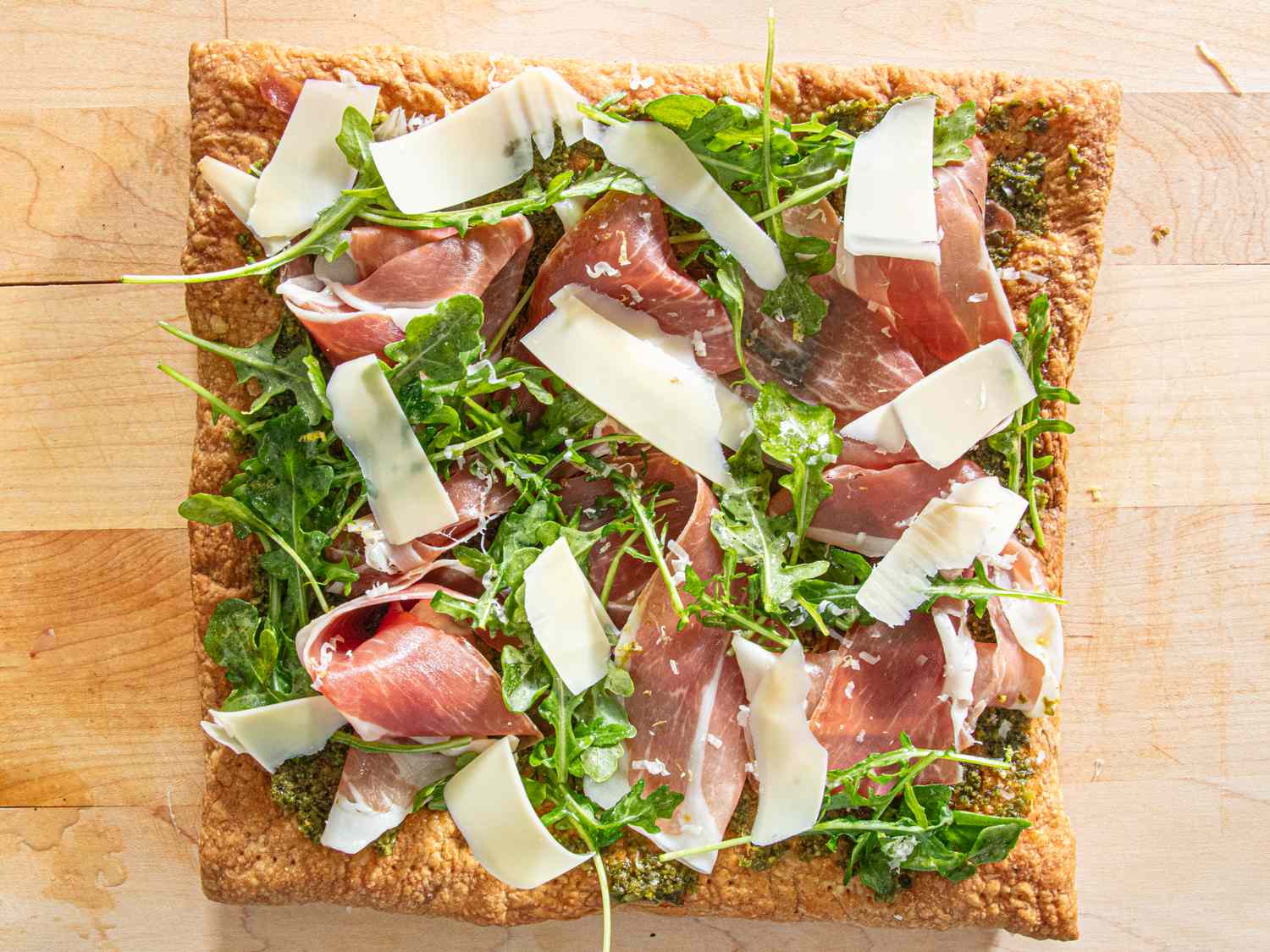 Charcuterie flatbread topped with arugula prosciutto and shaved cheese