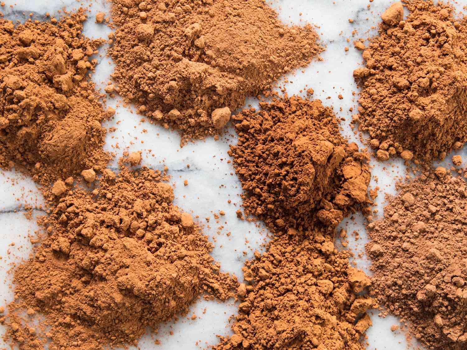 Six cocoa powders scattered on a marble surface