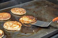 A person flips pancakes cooked on the Weber Slate 30 Inch Griddle