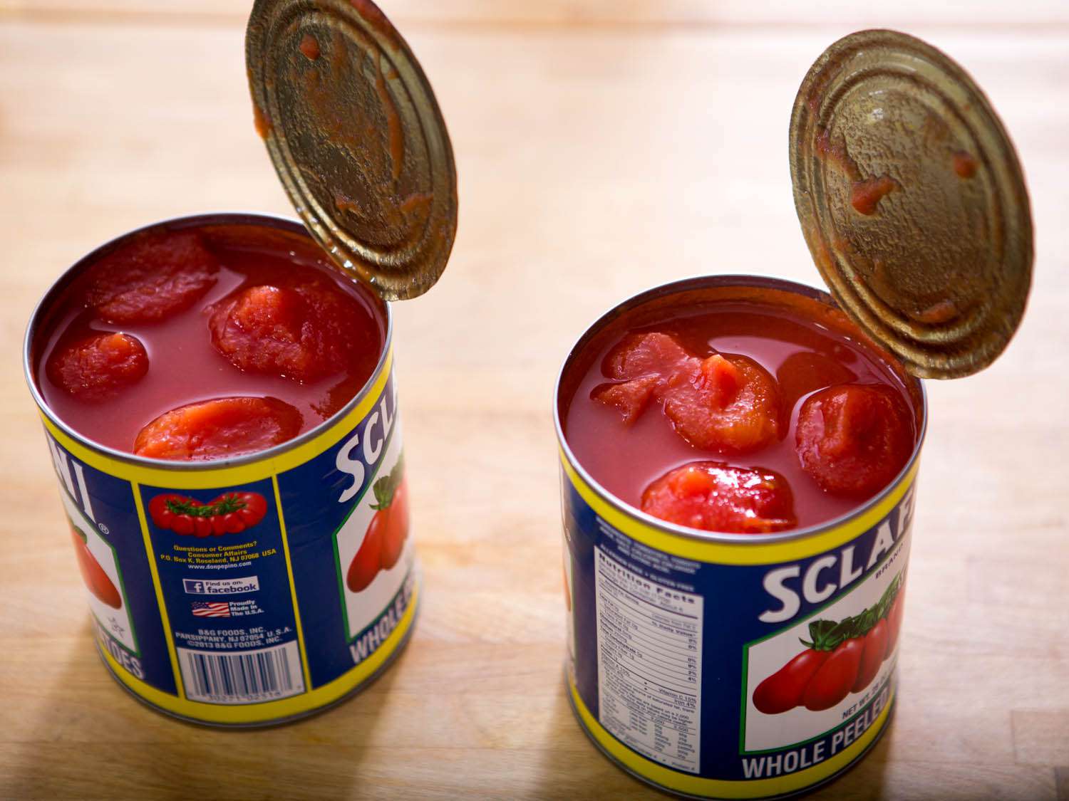 Two open 28-ounce cans of whole peeled tomatoes.