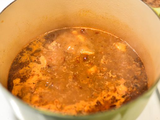 The braising liquid is simmered and reduced in a Dutch oven.