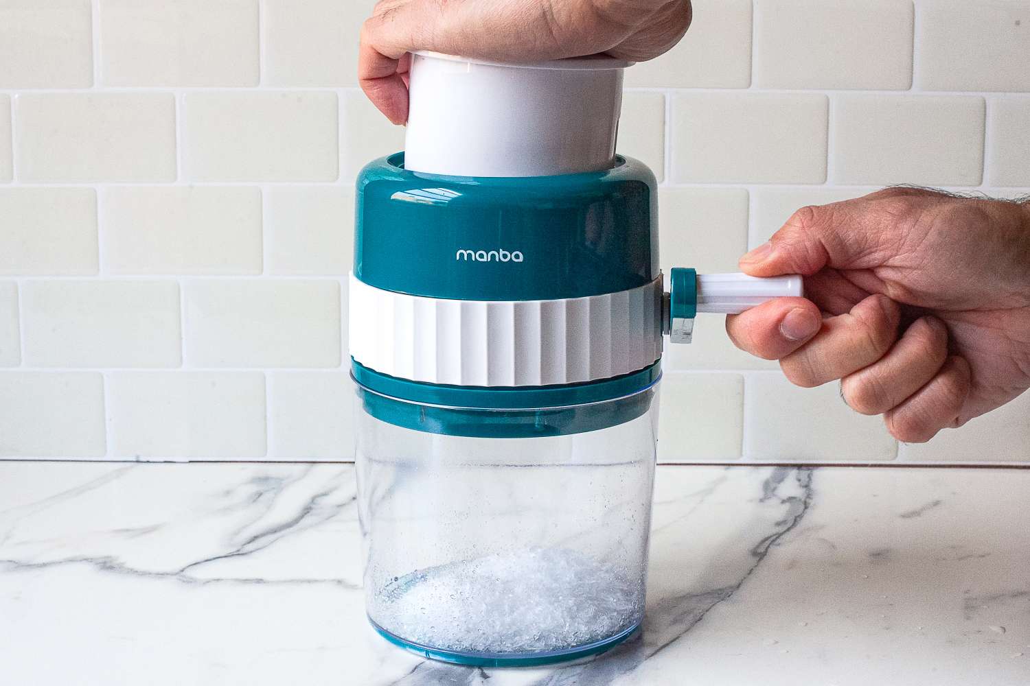 A person operating MANBA Ice Shaver and Snow Cone Machineon a marble counter