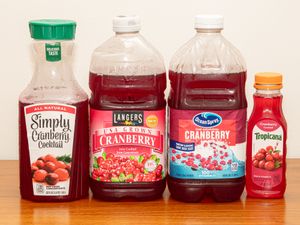Four cranberry juice bottles from different brands displayed side by side on a table