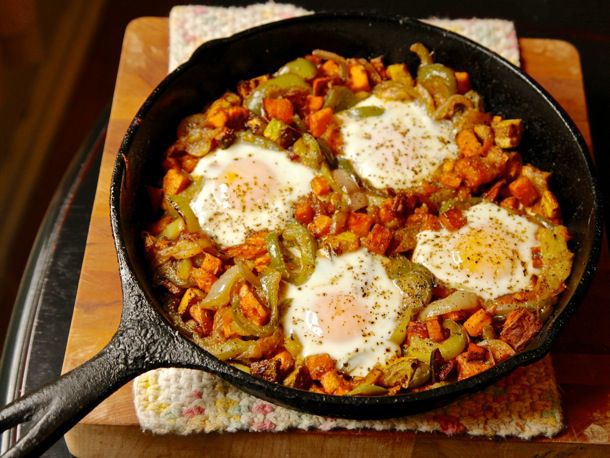 A cast iron skillet of sweet potato and pepper hash with baked eggs. 