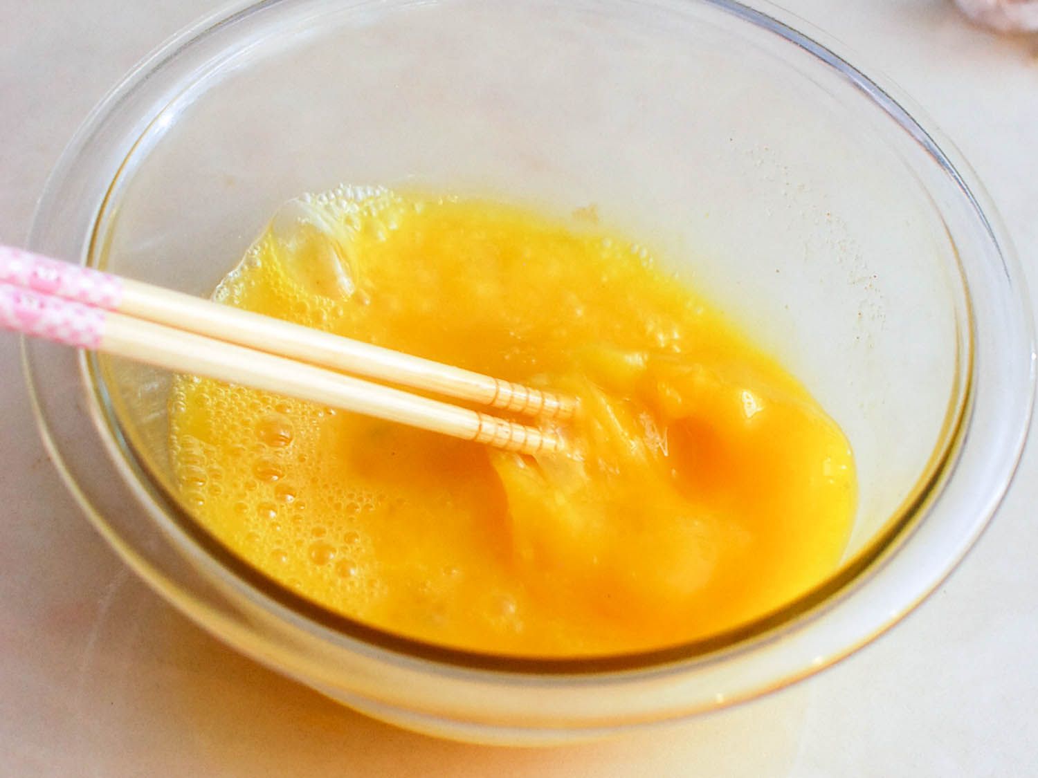 The egg mixture is beaten with chopsticks.