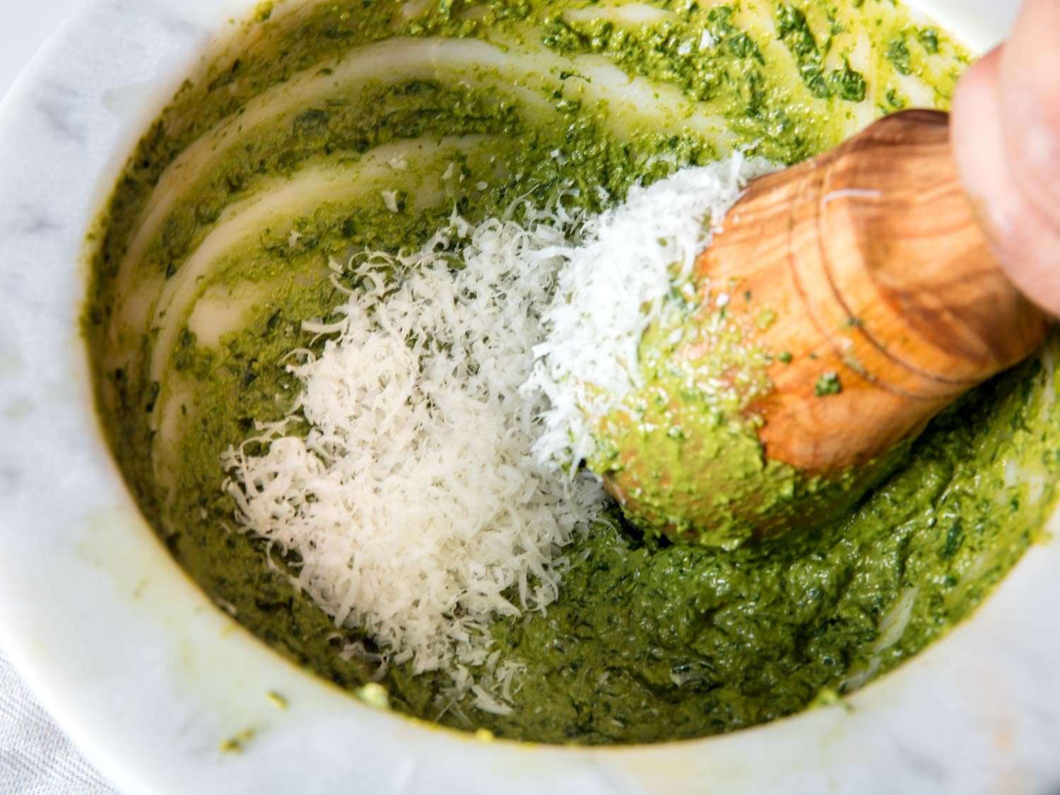 Adding Parmigiano Reggiano cheese to pesto