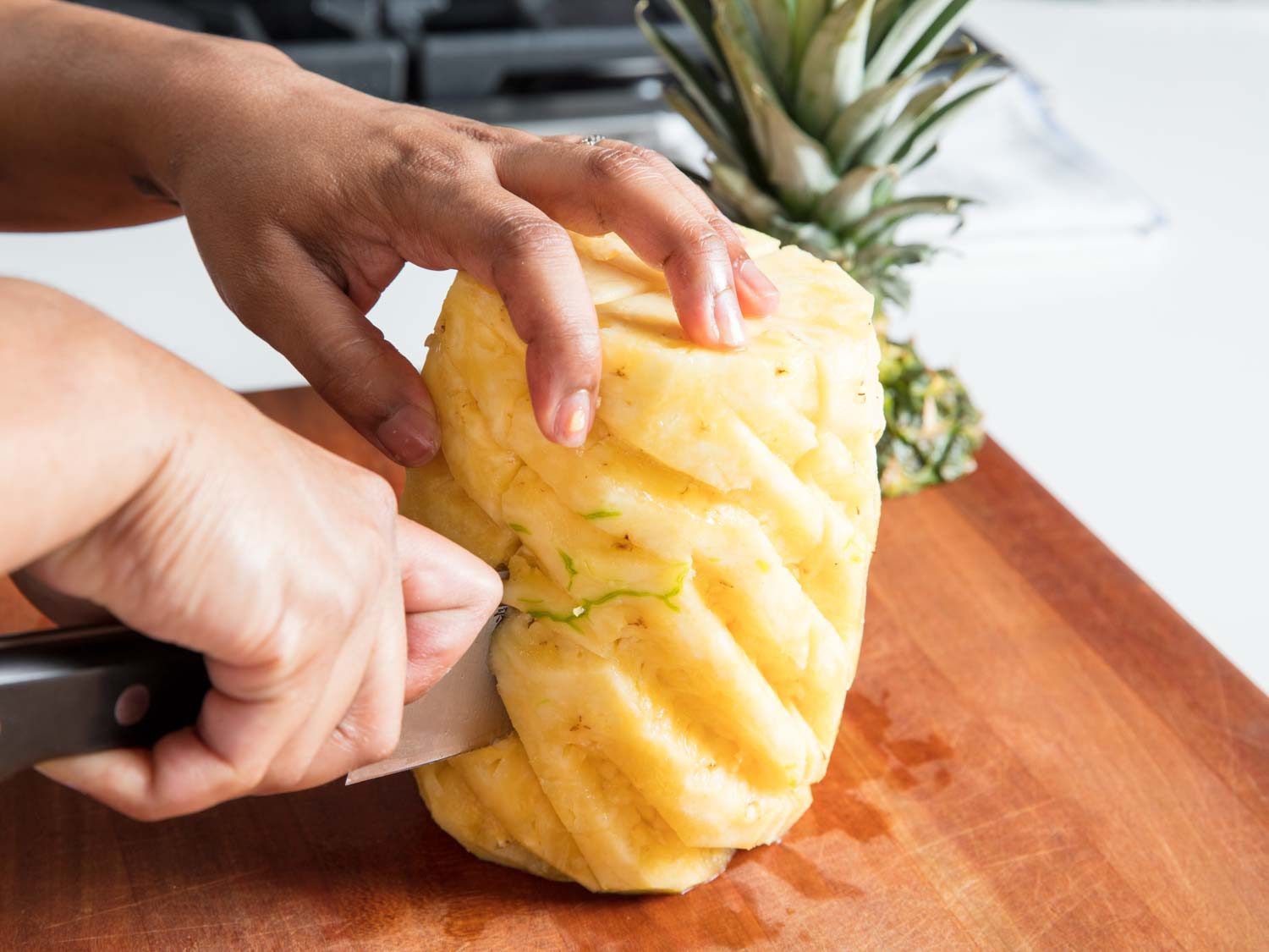 A knife slicing a pineapple into quarters.