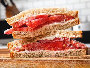 Classic tomato sandwich on a cutting board, cut diagonally and stacked