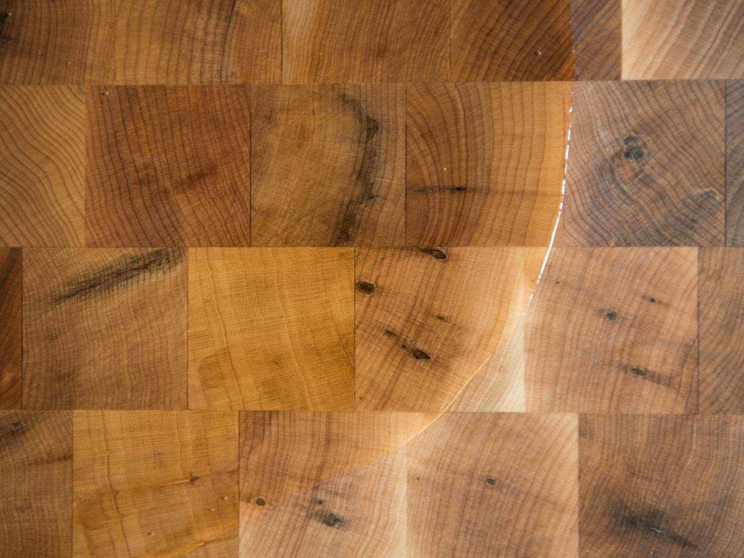 Overhead shot of mineral oil partially covering a wood board.
