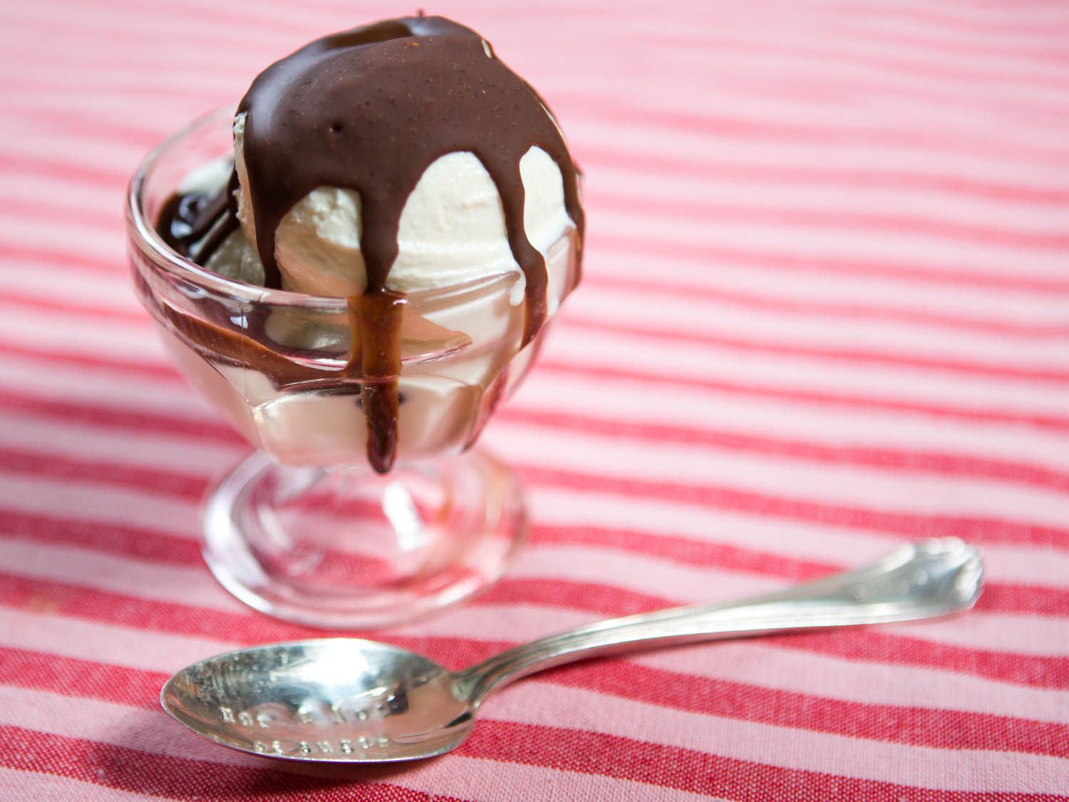 A scoop of ice cream in a small glass bowl, blanketed with magic shell.