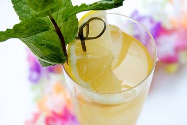 A Fog Cutter cocktail in a Collins glass garnished with a wedge of lemon and a sprig of mint.