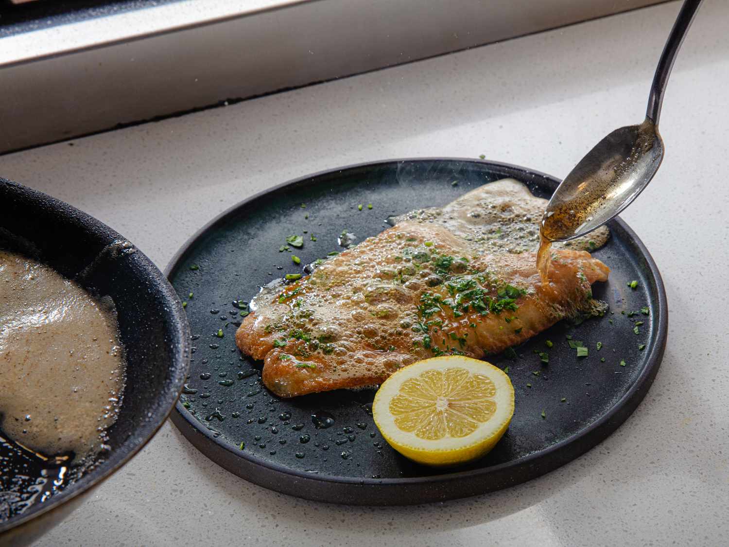 Hot brown butter being spooned straight from the pan over the fish.