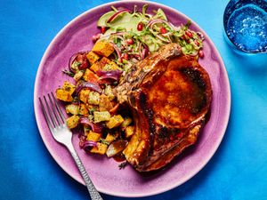 Dish with a glazed pork chop roasted vegetables and a fresh salad on a plate