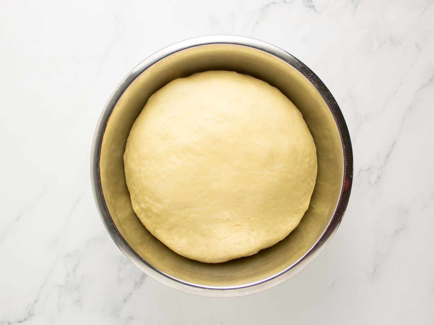Dough in metal bowl after it has proved and expanded in size