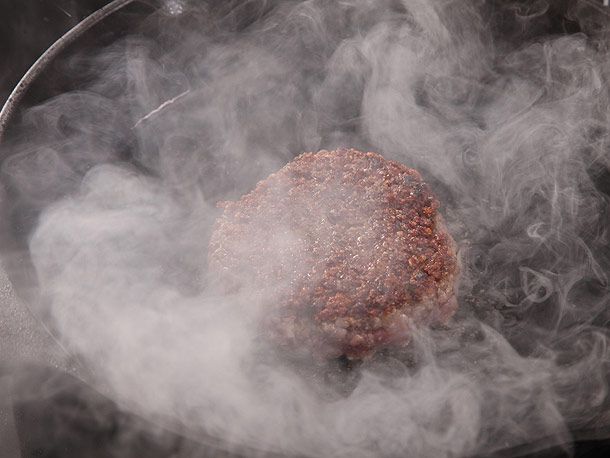 burger patty cooking on cast iron skillet