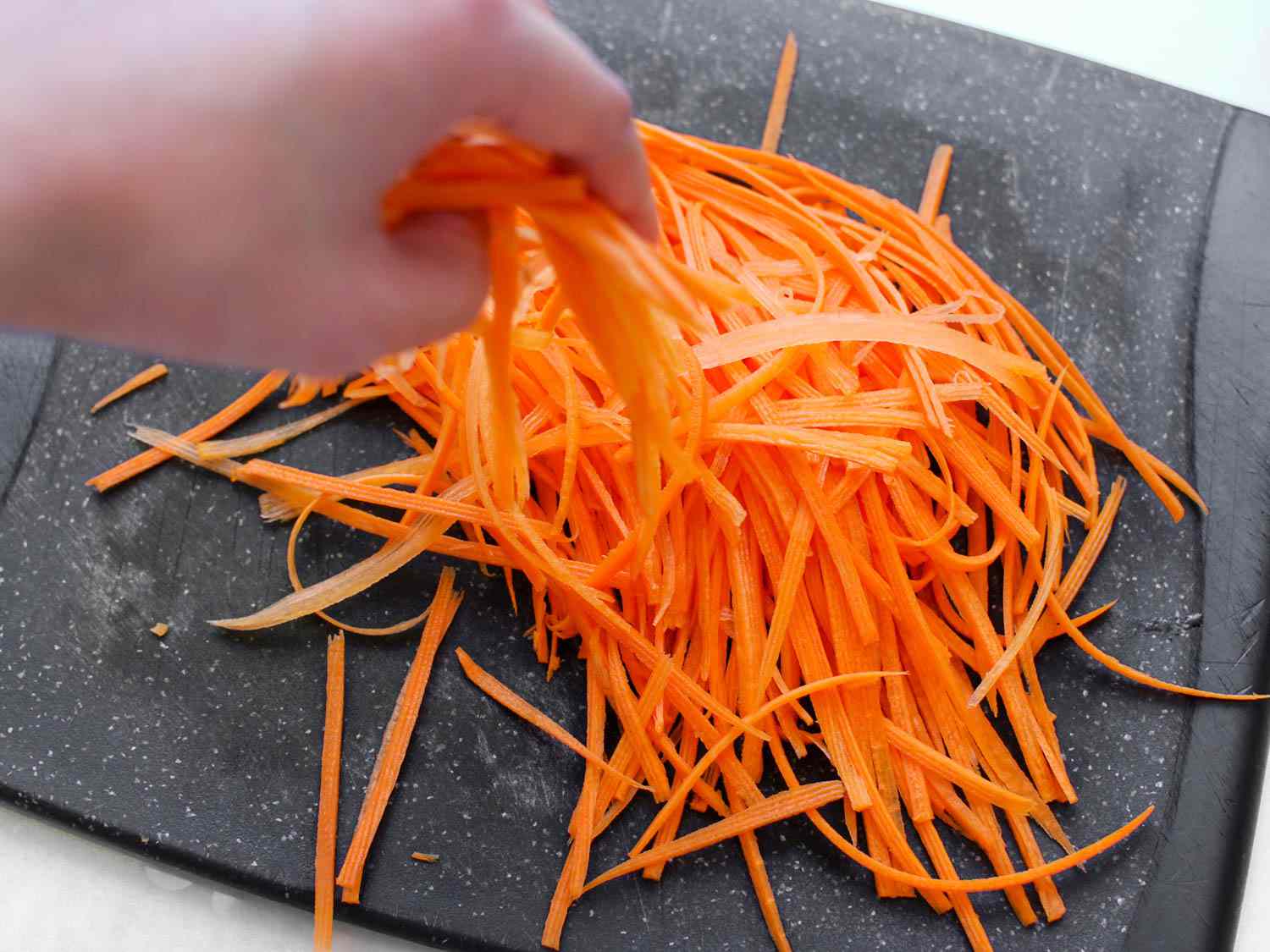 Pile of julienned carrots on a cutting board.