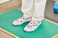 A person stands on the Fulton Standing Mat in socks