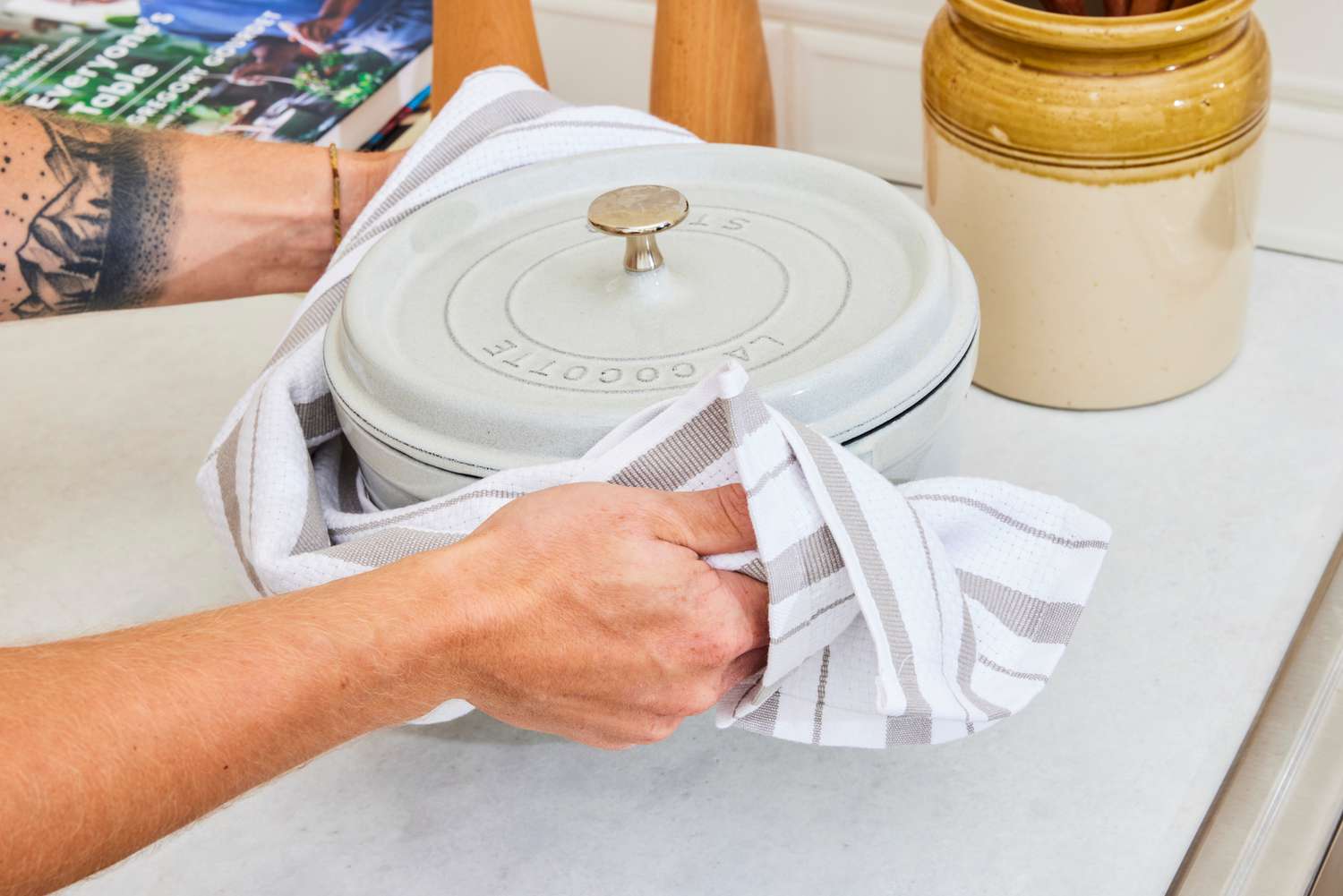 A person moving a Dutch oven using a dish towel.