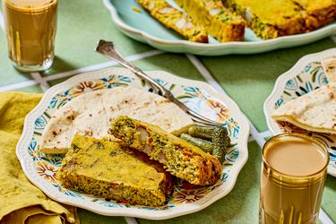 Dish of baked savory slices flatbread pickles and glasses of tea served on a table