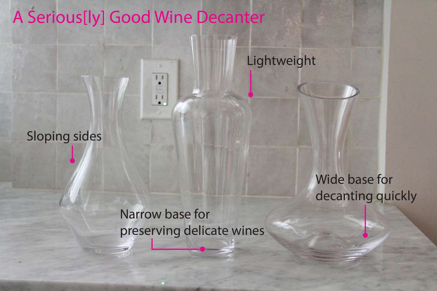 Three empty wine decanters on a marble counter