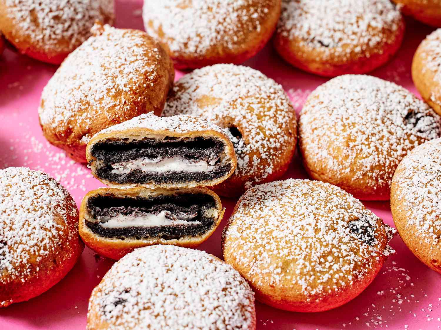pink platter of deep fried oreos with one cut in half to show insides 