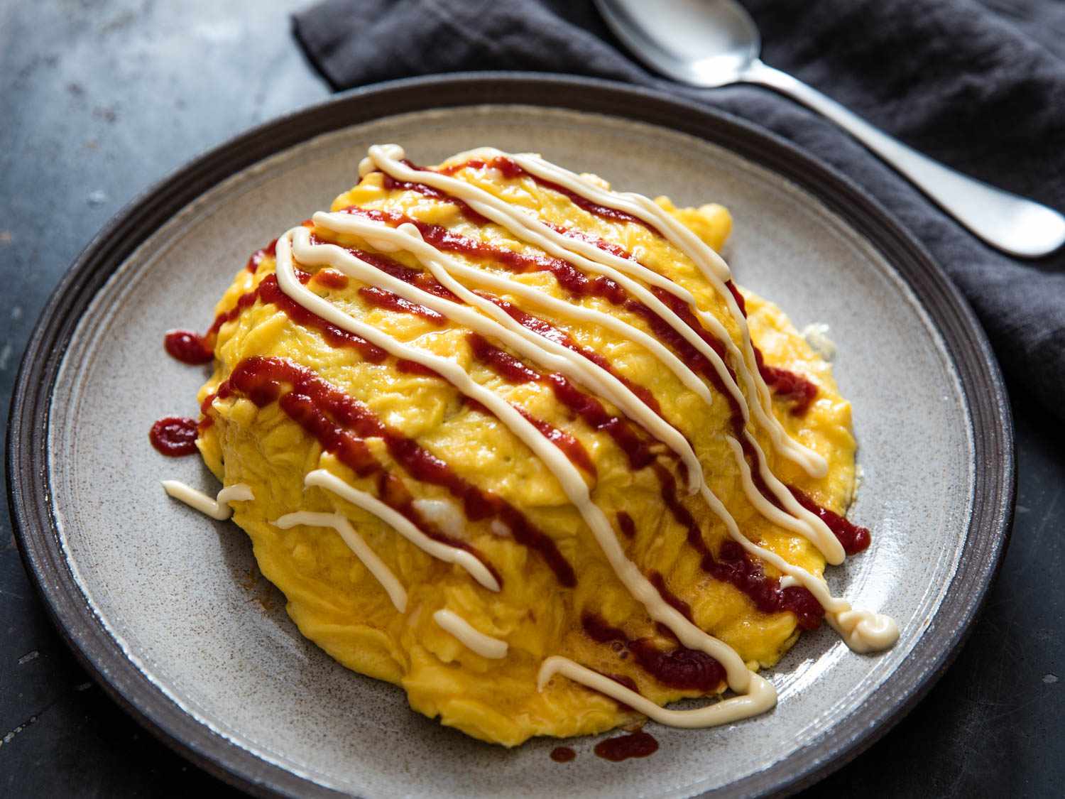 A mound of chicken omurice with squiggles of ketchup and Japanese mayo on top.