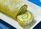Matcha Swiss roll on a white plate sliced to show the spiraled filling
