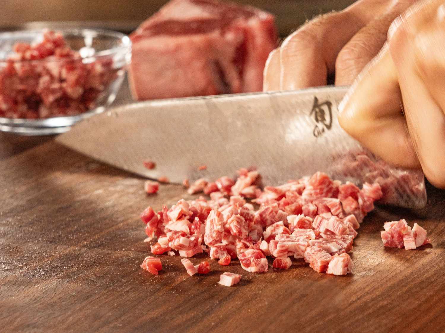 Dicing raw beef on a wooden board