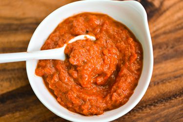 A small white bowl of ajvar, Serbian roasted red pepper sauce