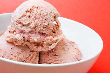 Closeup of a triple scoop of Strawberry Balsamic Ice Cream, served in a small white bowl.