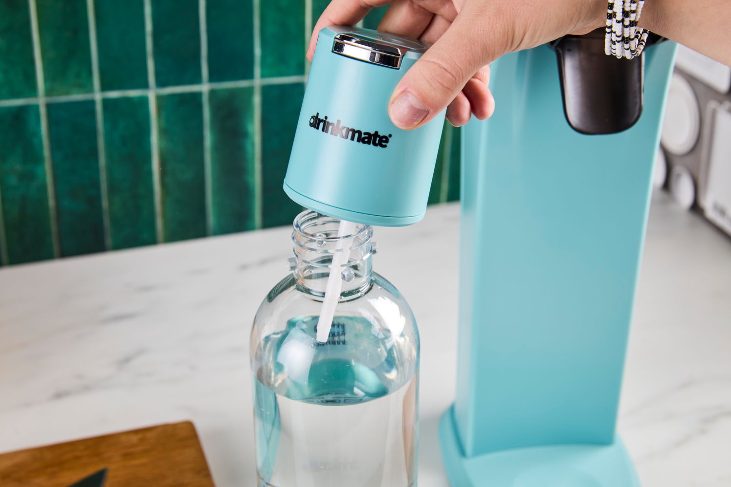 Hand using a Drinkmate carbonation device with a water bottle