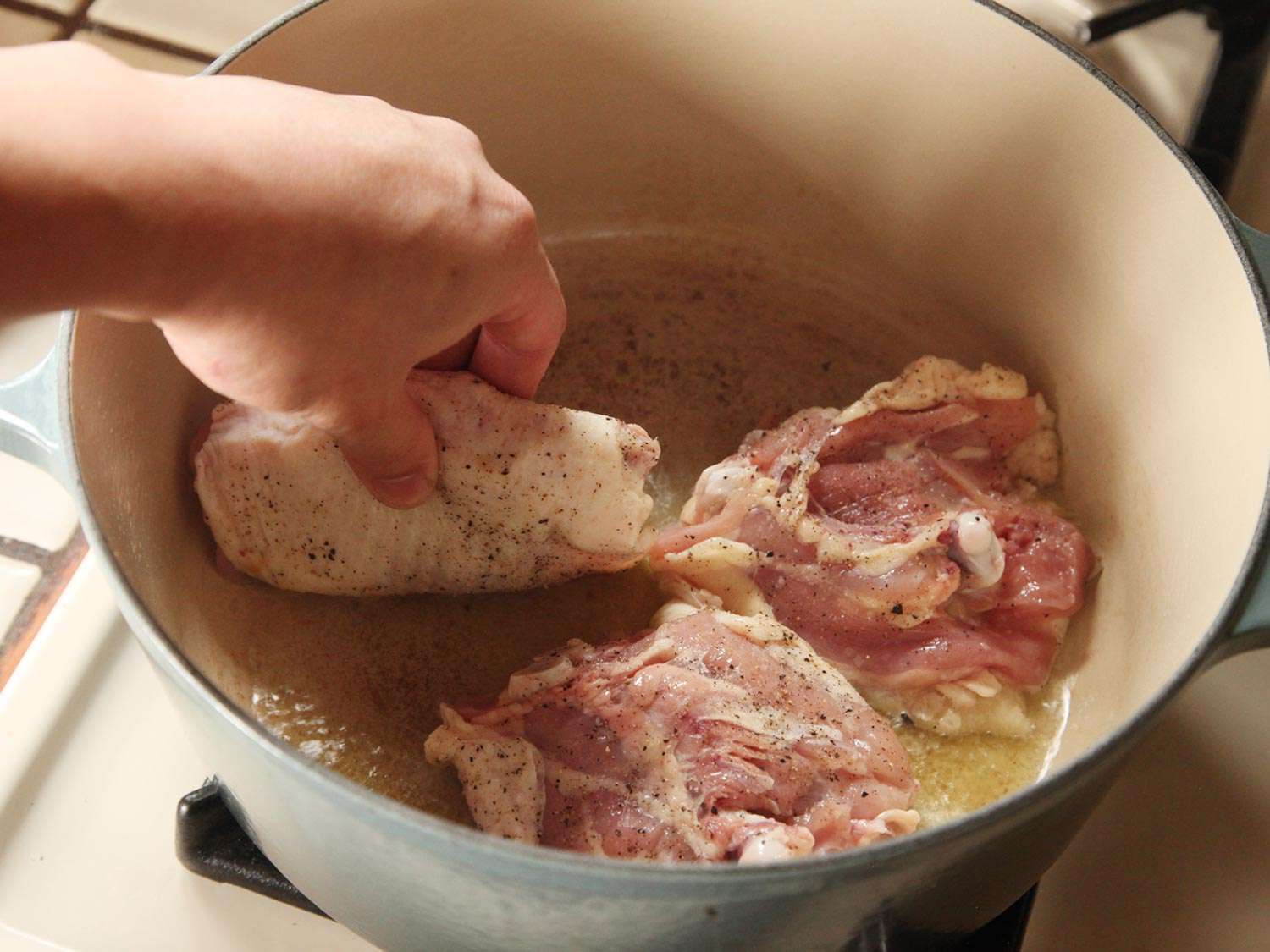 Chicken thighs are placed skin side-down in a Dutch oven to brown.