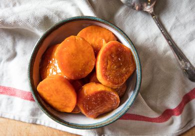Candied yams (sweet potatoes) in a blue and white bowl with a white towel underneath.