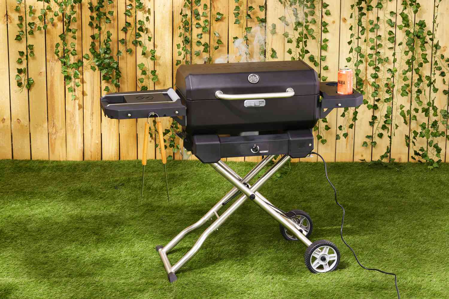 The Masterbuilt portable charcoal grill on a lawn.