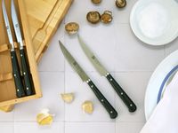 the zwilling porterhouse steak knives on a white tile surface with the box to the side